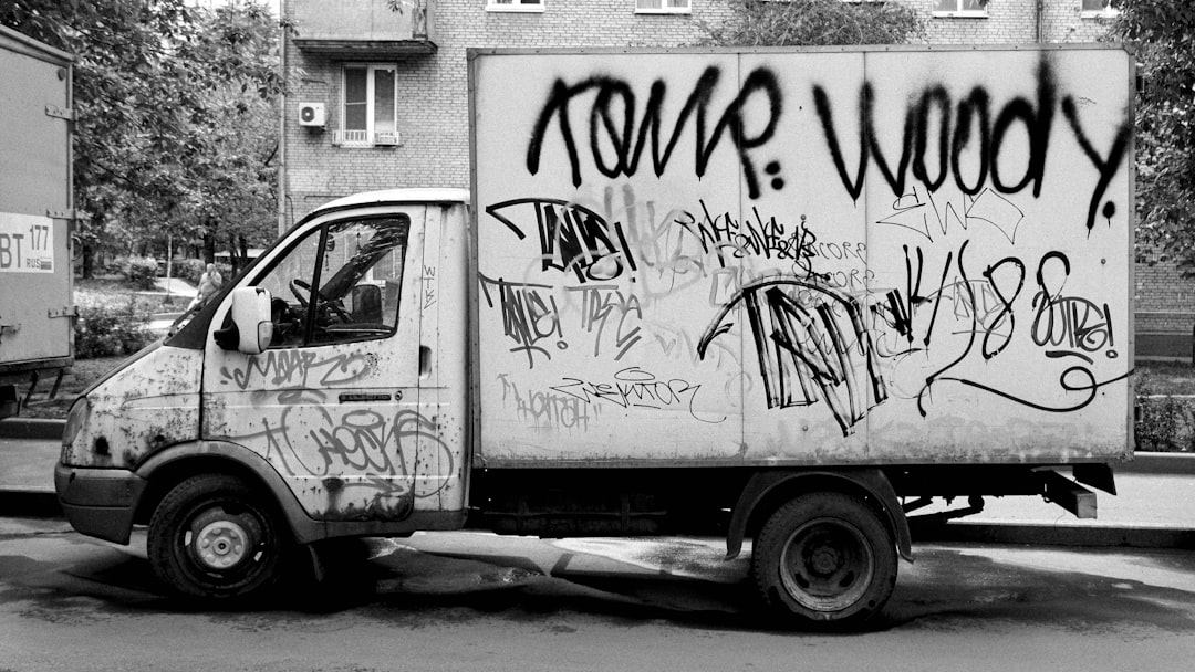 a-black-and-white-photo-of-a-truck-covered-in-graffiti-l80wv9po6ky