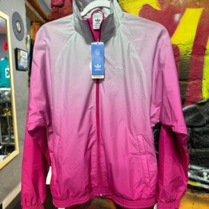 Esta chaqueta marca Adidas es un modelo deportivo de estilo windbreaker en tonos rosa y gris. 
